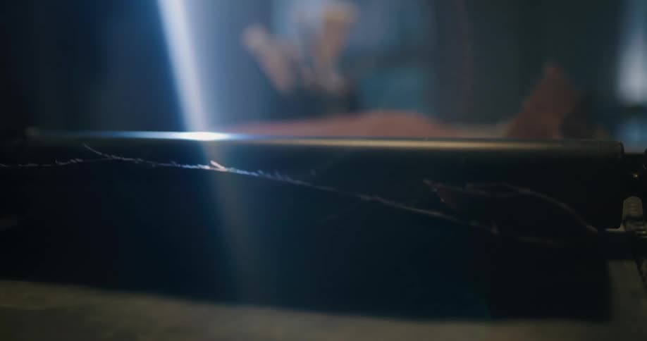 A woman uses a large tabletop tool to smooth out a large piece of leather fabric