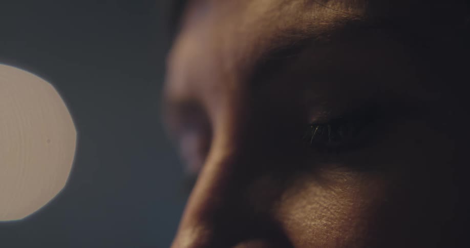 Person blinks and sways as light and shadow play over face