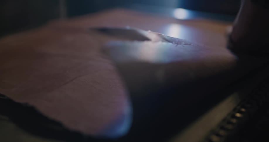 A person in a room placing a piece of leather on a roller