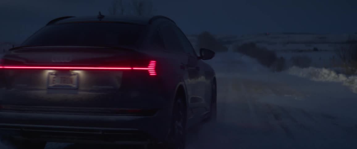 A vehicle drives at night on a snow covered road