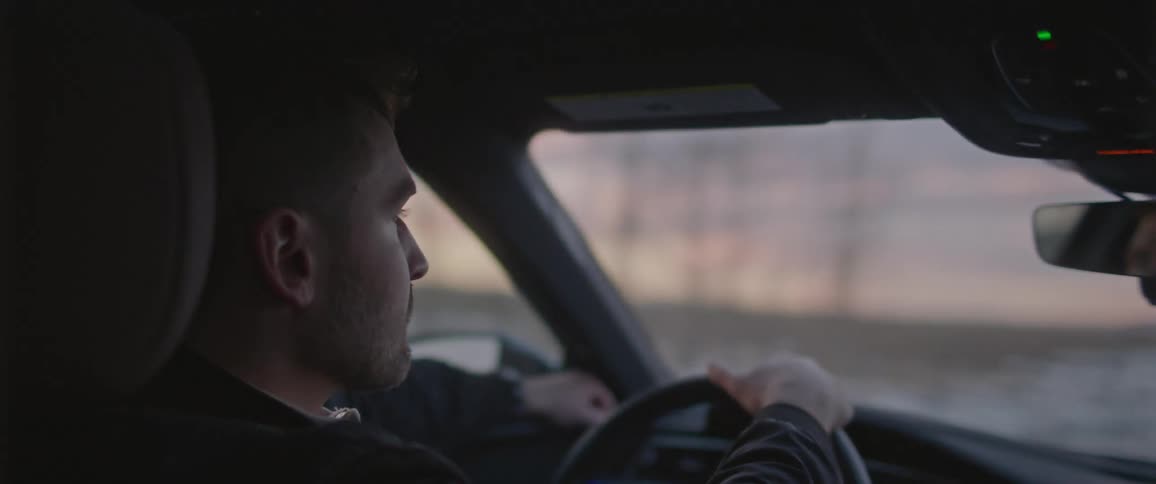 A young man is driving a car on asnowy road
