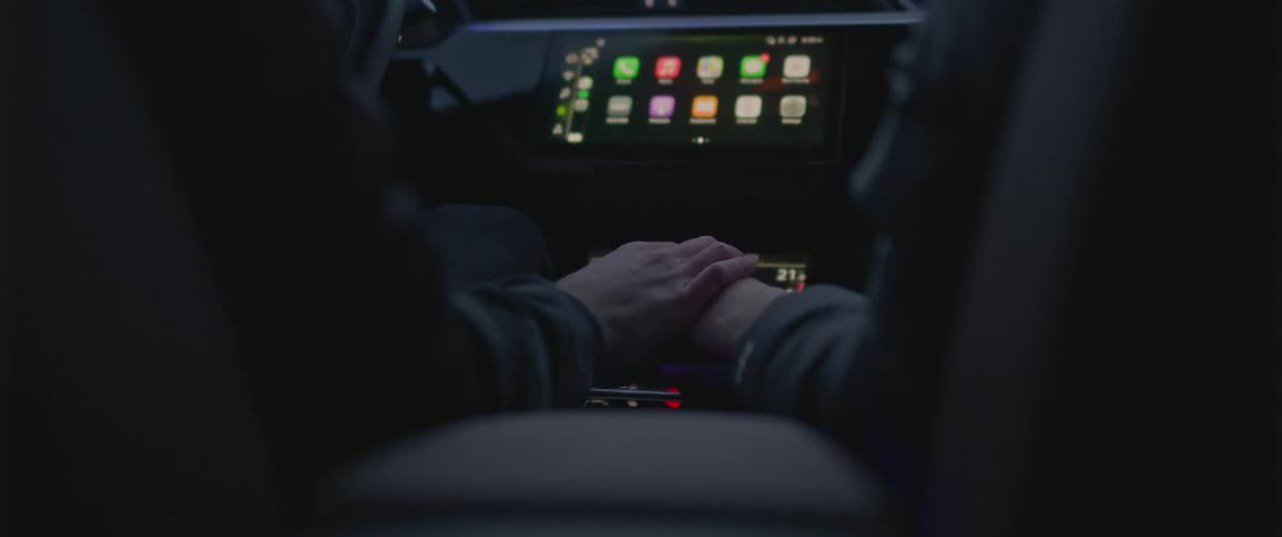 A man and a woman in a vehicle holding hands with the dashboard in the background