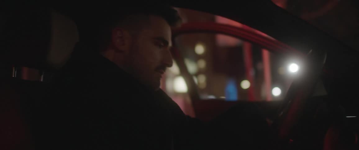 A man is getting into a parked vehicle at night