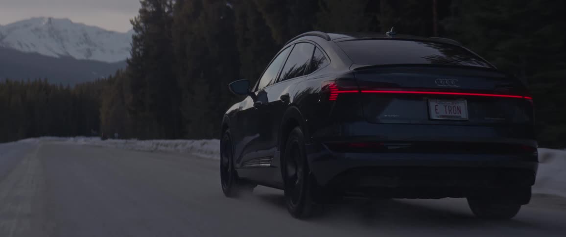A car is driving on an empty road in winter