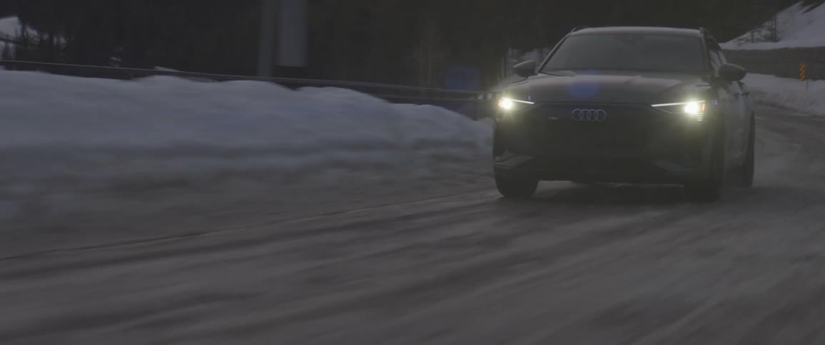 Black car driving on a snow covered road in the countryside at morning