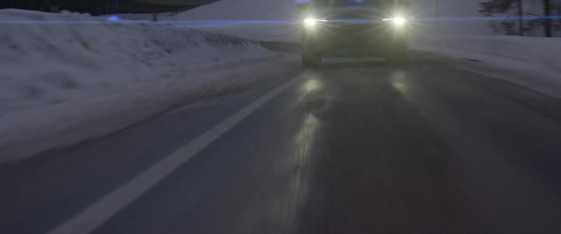 A car driving up a mountain road in the winter