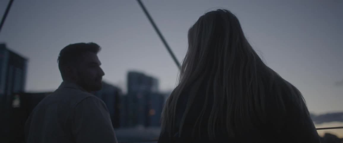 A man and a woman holding hands with buildings the sky and clouds in the background