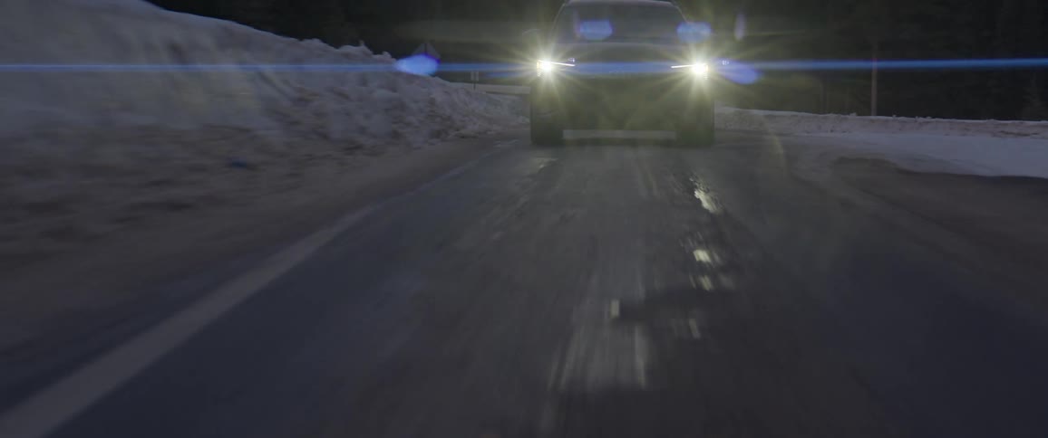 Black car driving on a snow covered road in the countryside at morning
