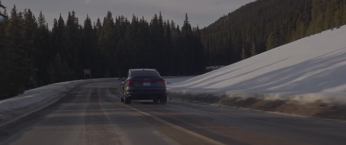 A car driving down a mountain road with snow
