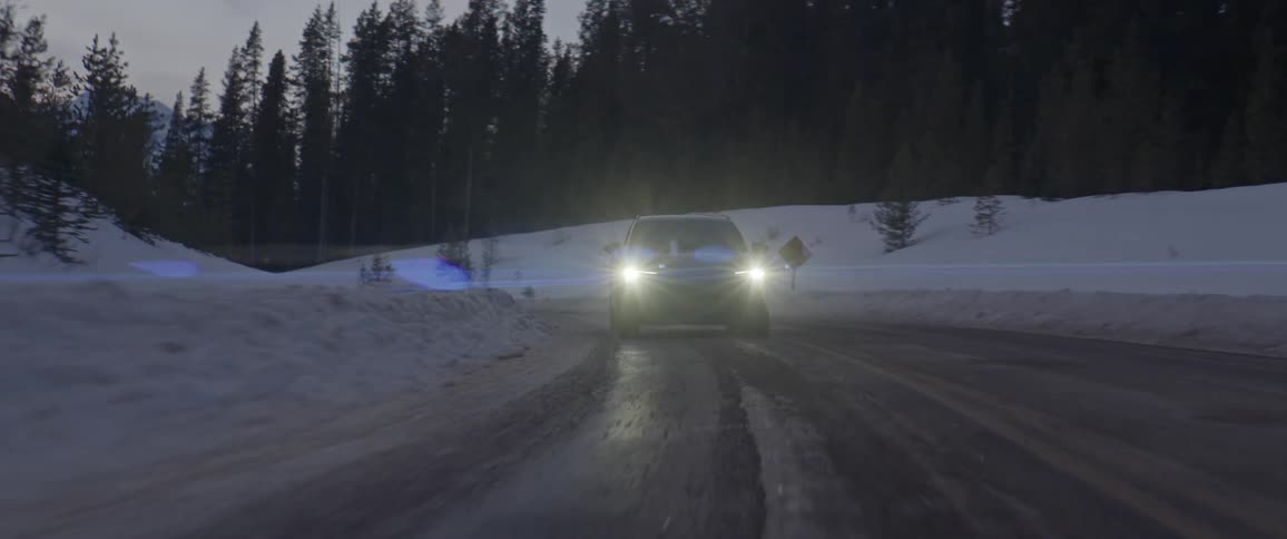 A sport utility vehicle drives down an icy mountain road