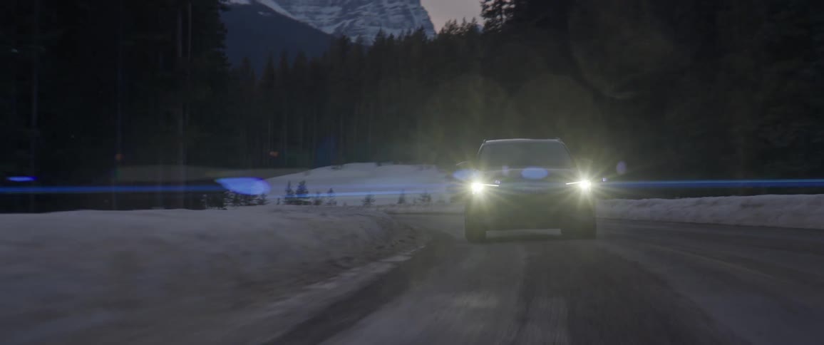 A car is driving on a road in winter near the mountains