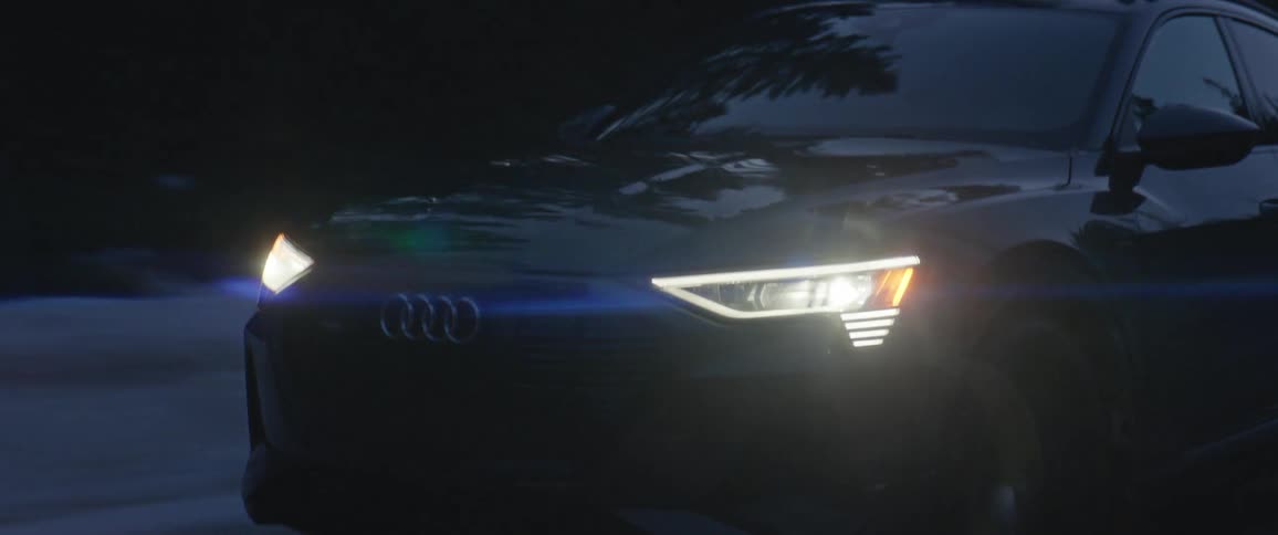 An audi vehicle drives along a snow covered rural road