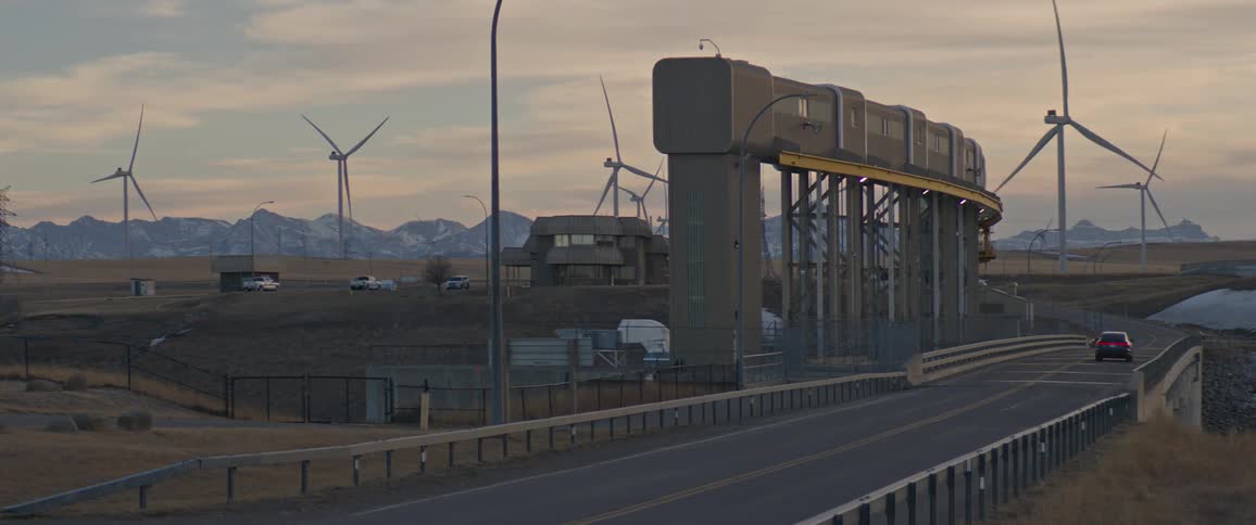 A car drives past a wind farm