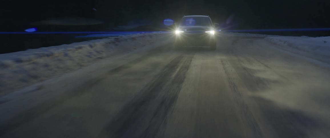 Black sports car with headlights on driving on a rural road in the countryside at night