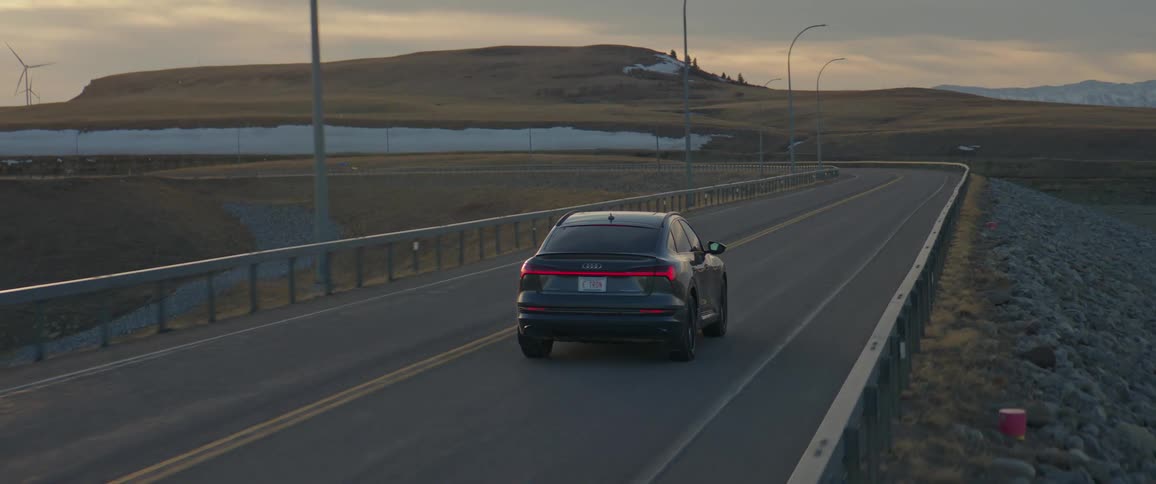 A car is driving on an empty highway at dusk
