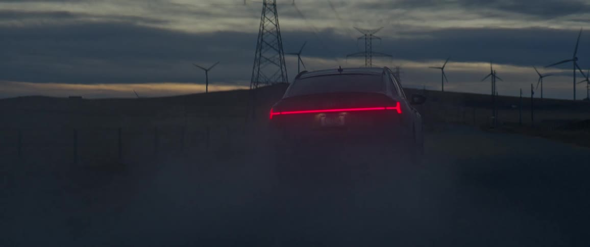 A vehicle drives beside a wind turbine farm
