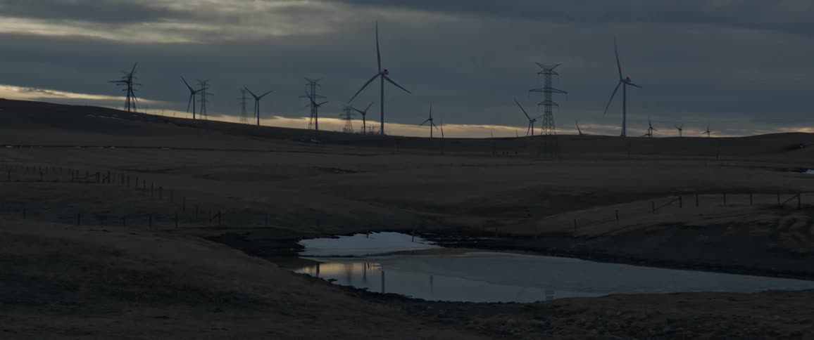 Turbines spinning on a wind farm on the hills at evening