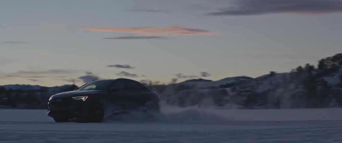 Black sports car parked on the white plains of a desert near the mountains at sunset