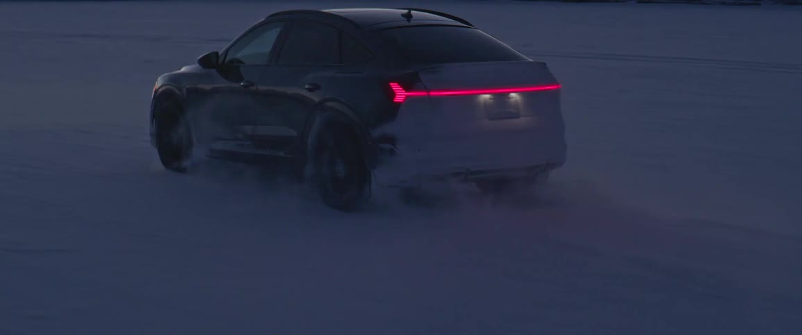Black car driving on a snow covered desert near the mountains at morning