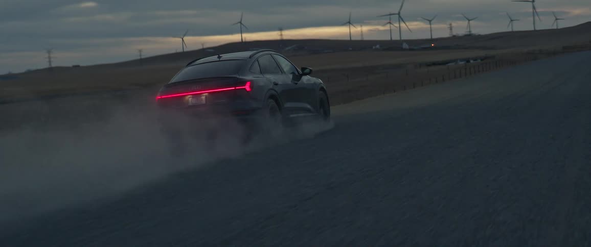 A car is driving down a rural road at dusk