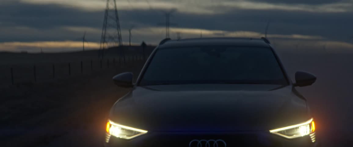 A vehicle driving on a road with wind turbines the sky and clouds in the background