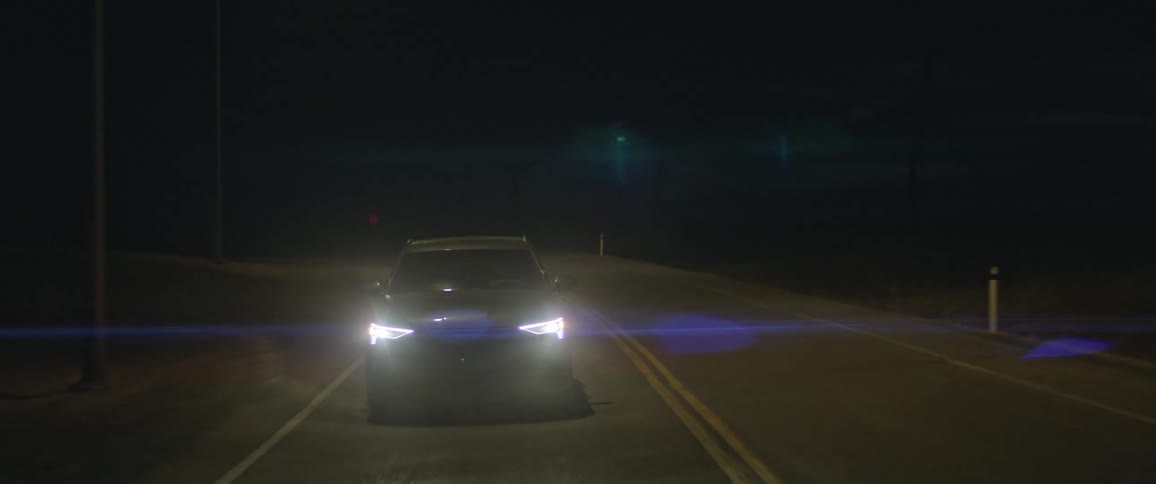 An audi car is driving on the road with headlights on during night time
