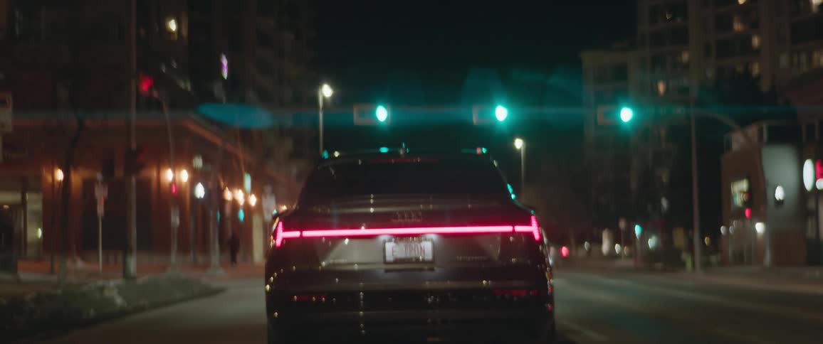 Dark grey audi car travels in city street at night