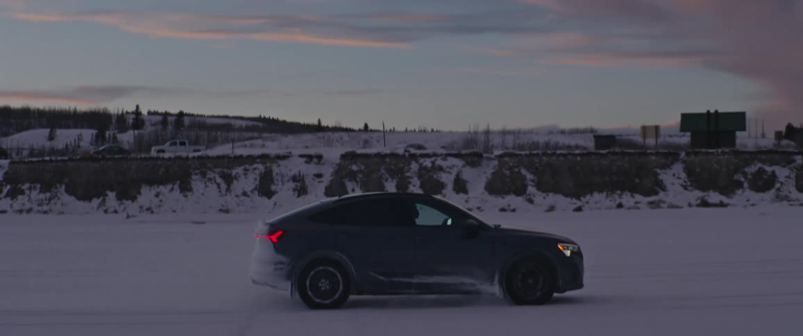 A car is driving in winter while the sun is setting