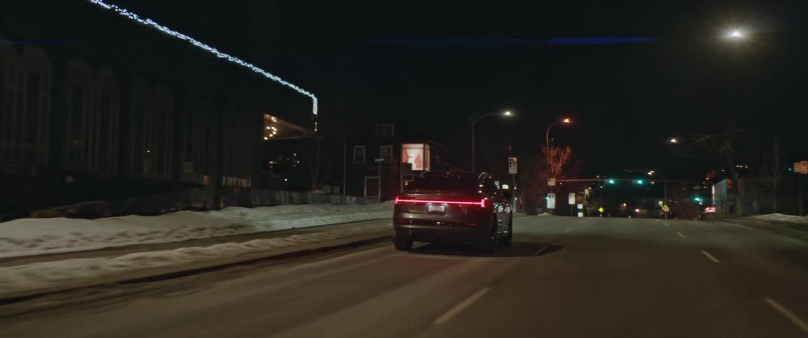 A vehicle driving on a city street with traffic lights streetlights and buildings in the background