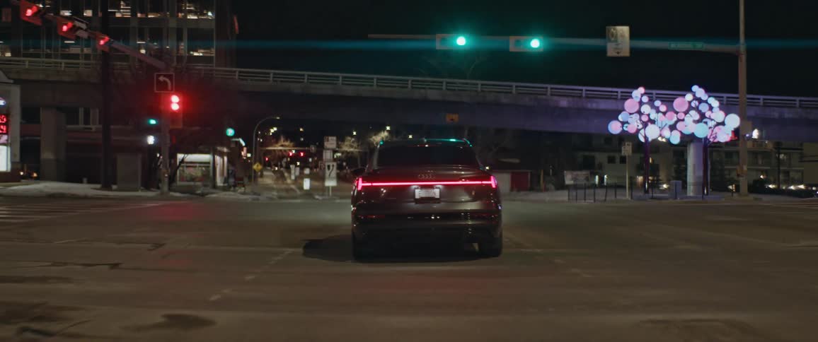 A vehicle driving on a city street with an overpass trees buildings and the sky in the background