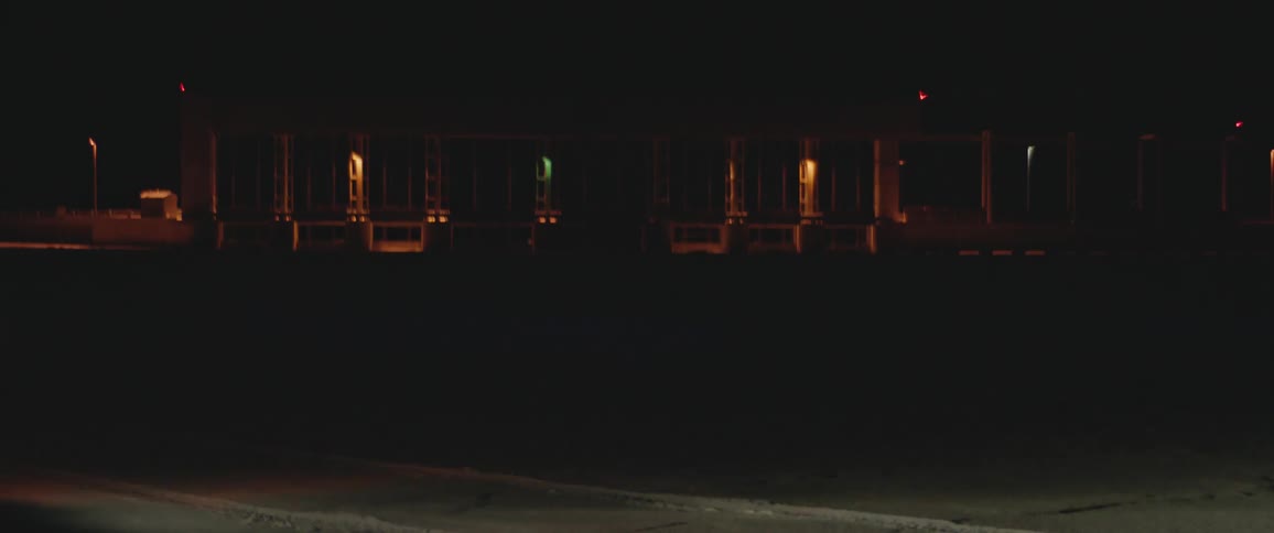 A car drives by in front of a building during night time