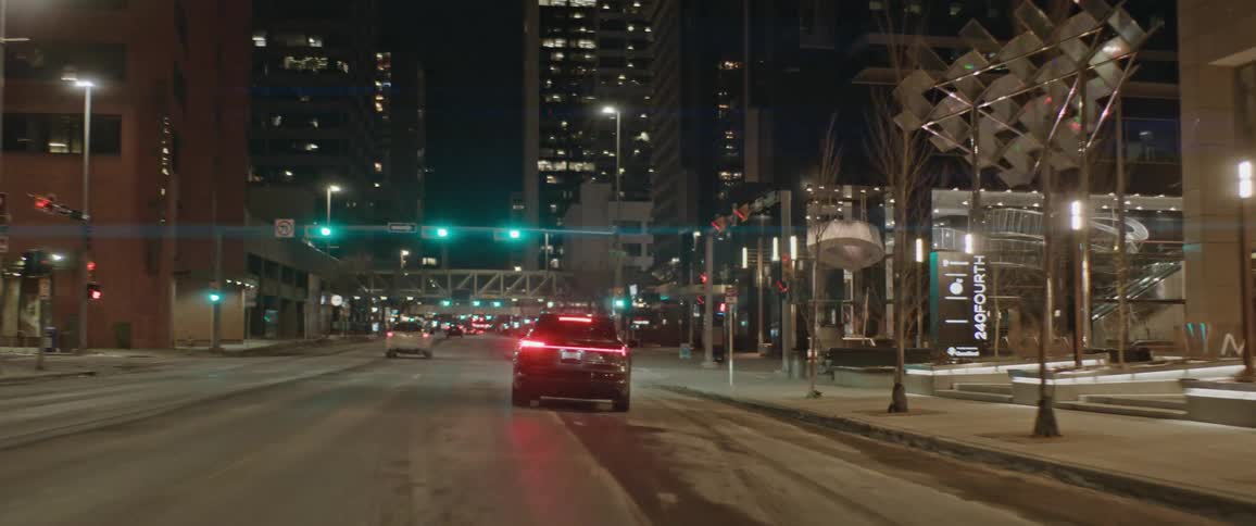 Cars are driving down a busy street in a downtown city