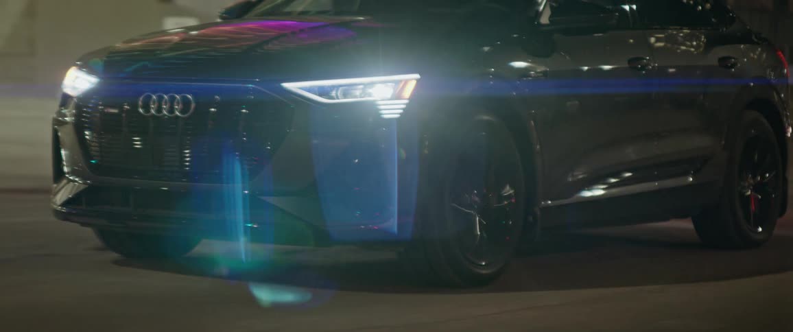 Audio sedan drives along city street past intersections at night