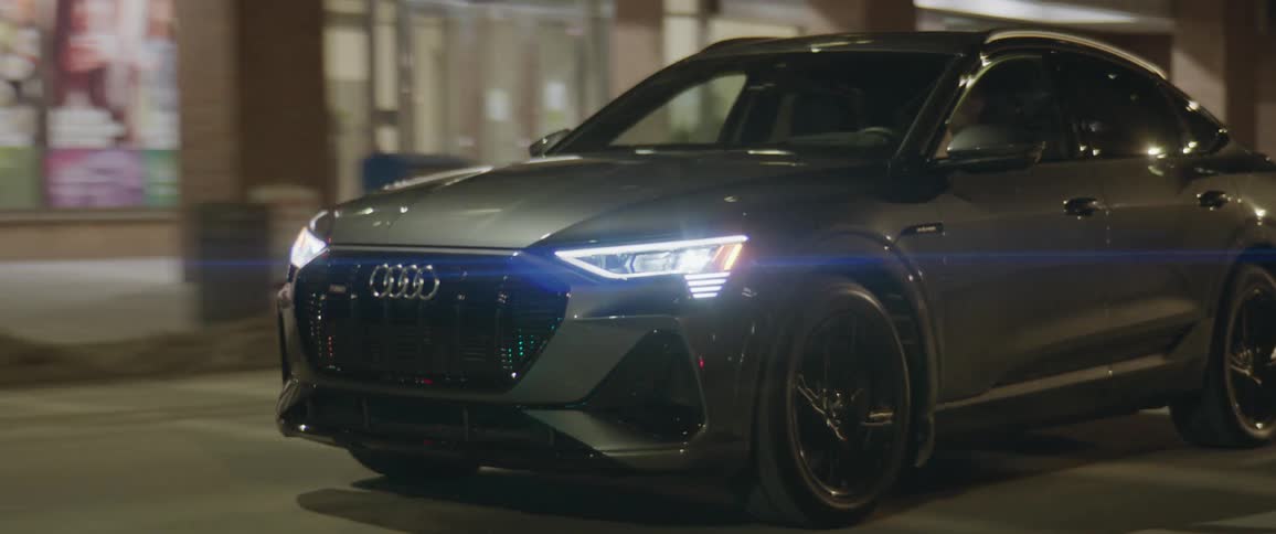 An audi car driving on a city road during night time
