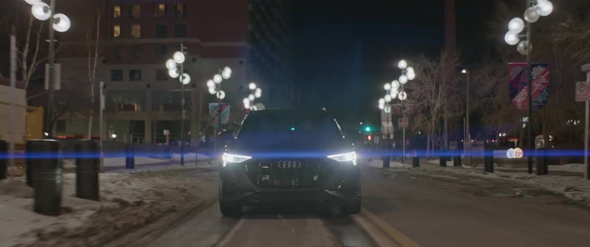 A car is driving on a street in a downtown city at night