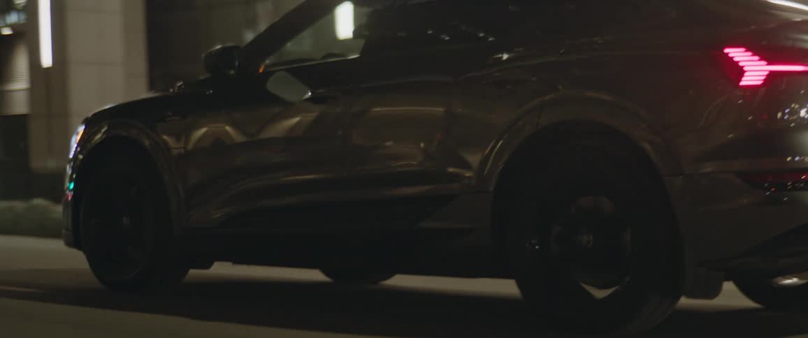 A vehicle driving on a city street with buildings in the background