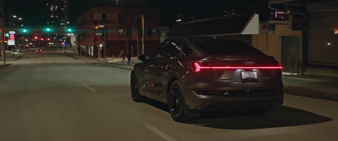 Dark grey audi car drives on city street at night