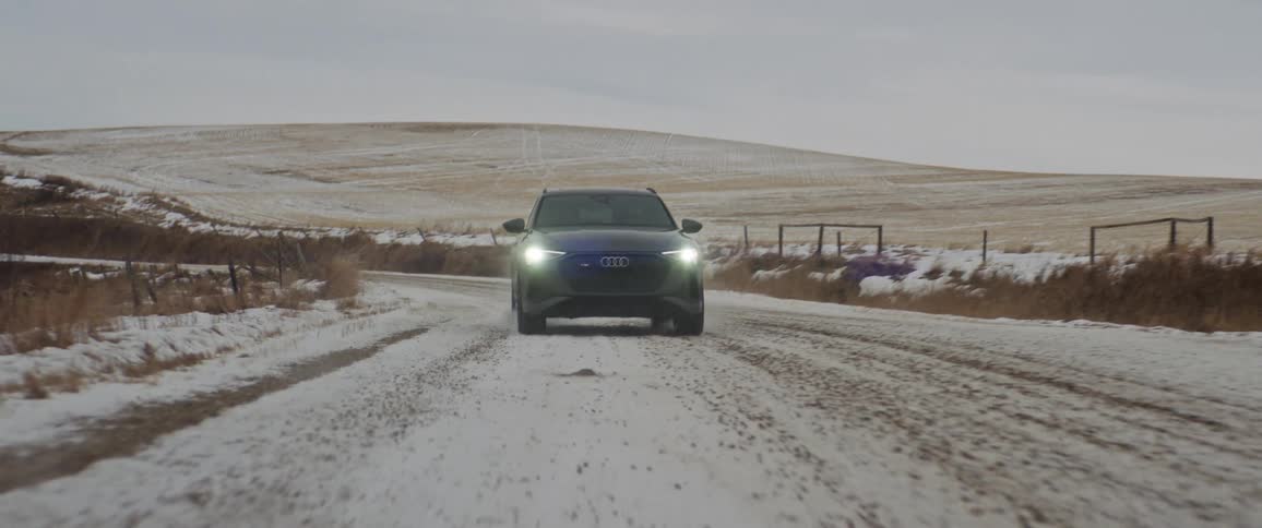 A view of a car driving through the snow outdoors
