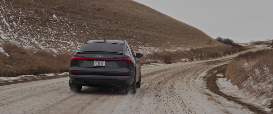 Black car driving on a snow covered road in the countryside at morning