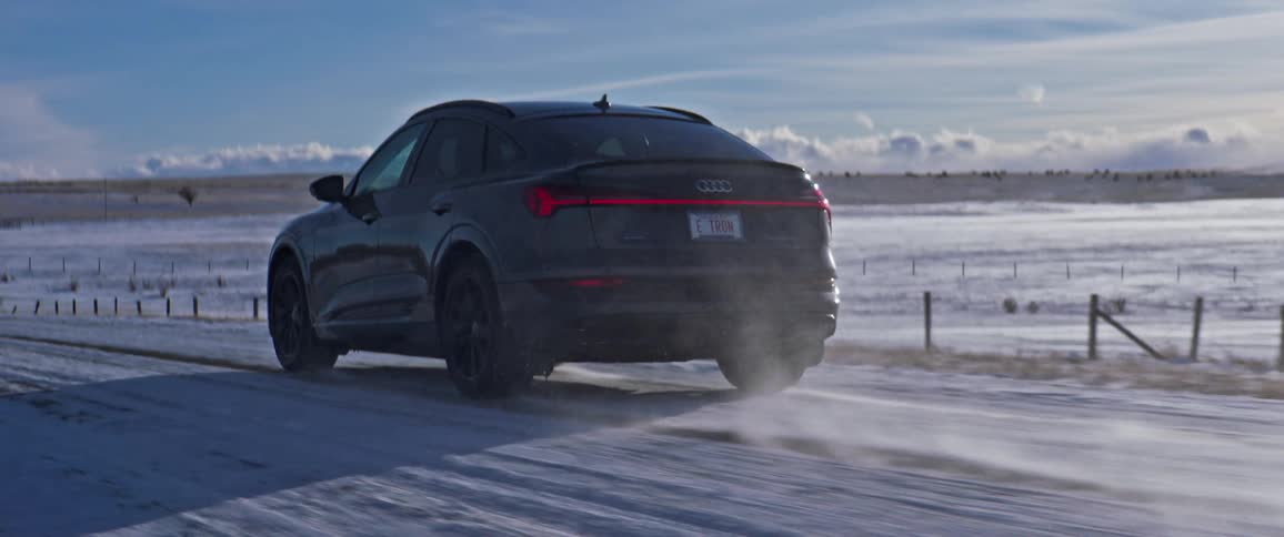 An audi vehicle drives on a rural snow covered road