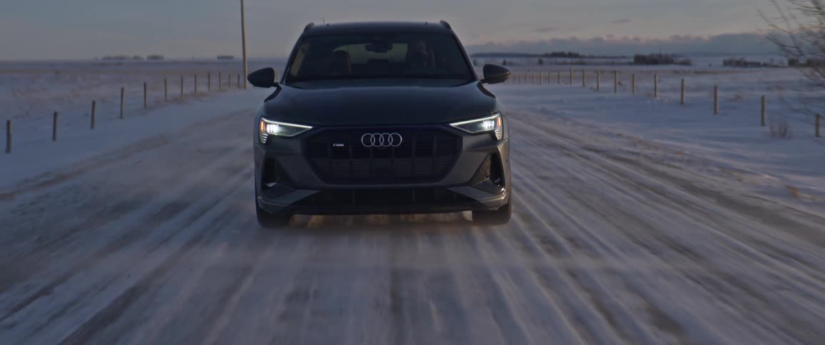 Black car driving on a snow covered road in the countryside at morning