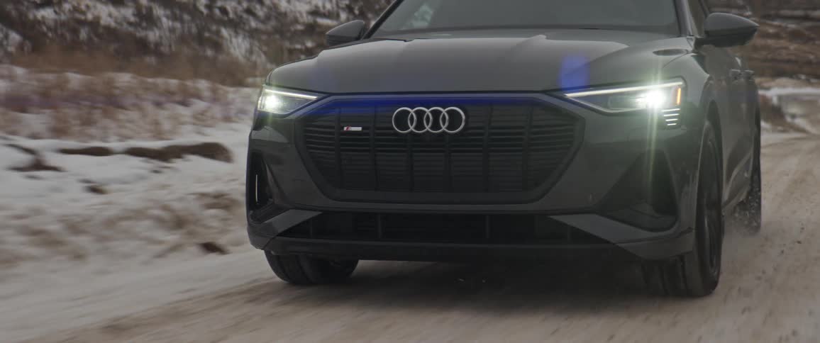 A car is driving on a gravel road in winter
