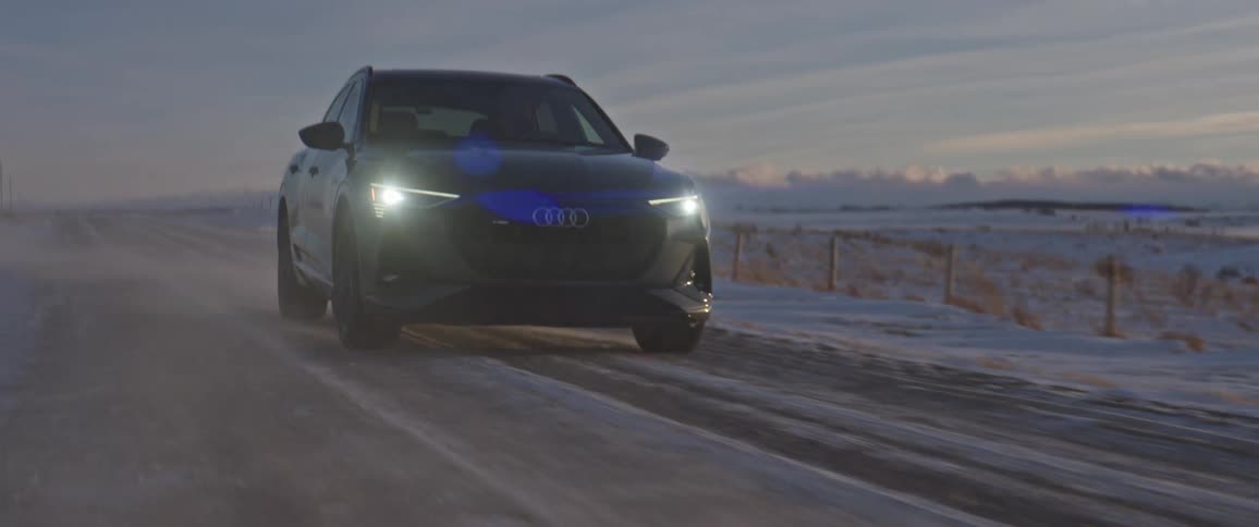 Black car driving on a snow covered road in the countryside at morning