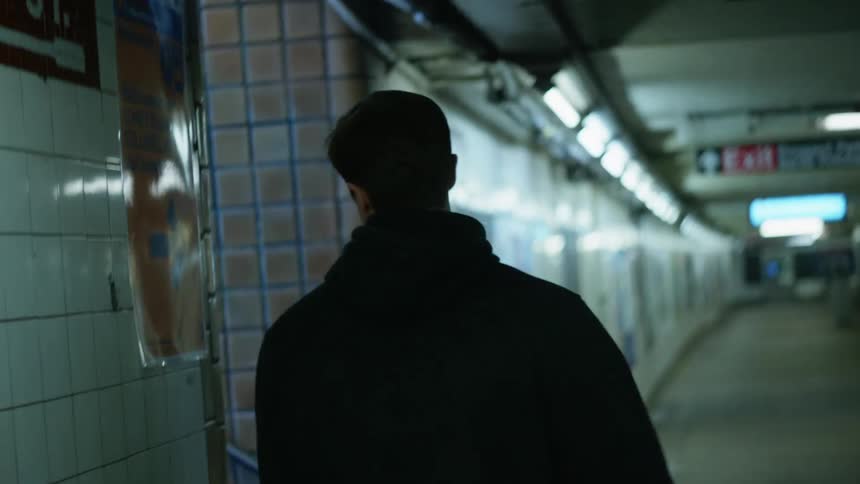 A man that is walking through a subway terminal then turns to exit up the stairway