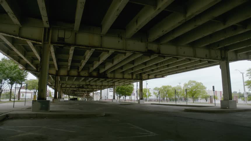 An underpass with vehicles trees the sky and clouds in the background