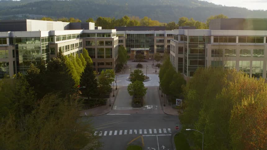 The gleaming windows of a modern office complex reflect the early morning sun