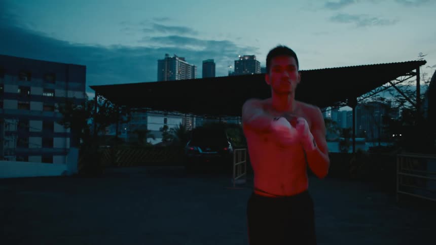 An asian man is jogging outside while practicing shadow boxing