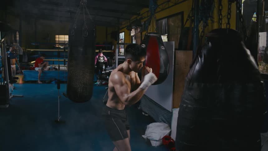 A male boxer punches in the multiple times inside a gym