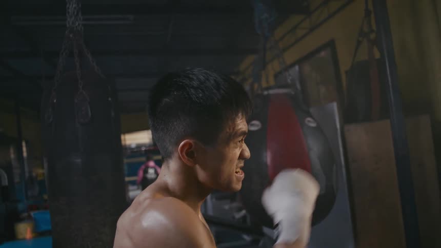 Sweating bare chested boxer jabs and practices in gym