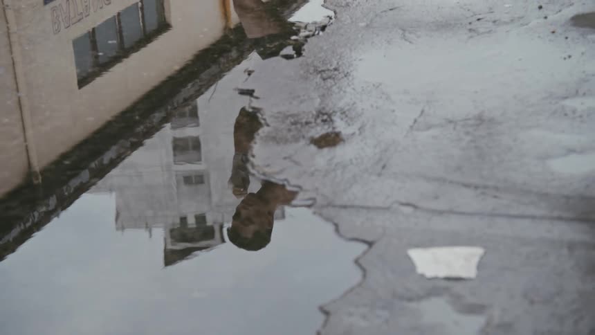 Shirtless muscular man shadow boxing reflected on a puddle in the city